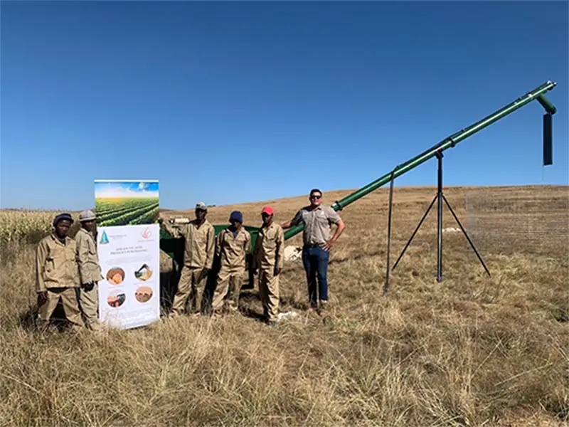 Farming team beside a grain auger in a Free State field