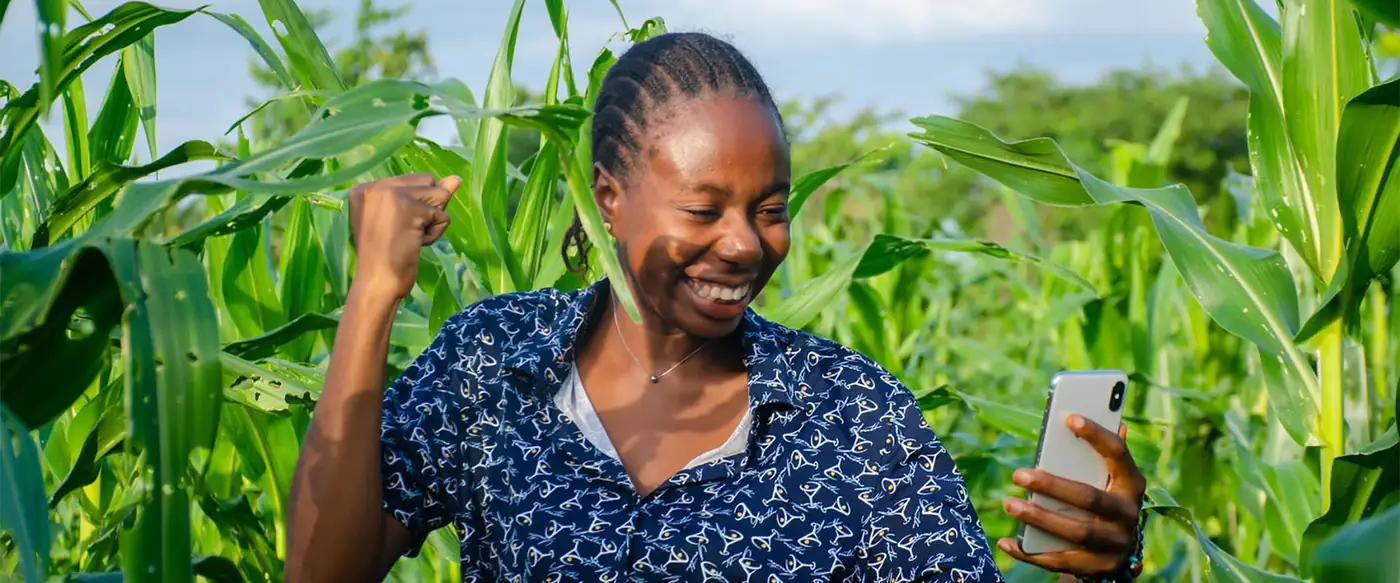 A smiling woman standing in a field of young maize